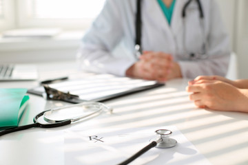 Stethoscope next to hand of doctor  reassuring her female patient. Medical ethics and trust concept