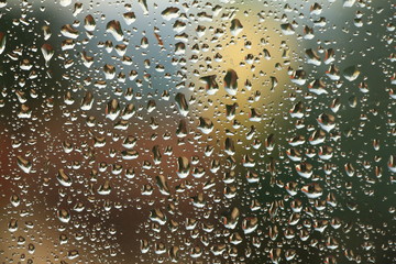Rain drops on window with house and church in background