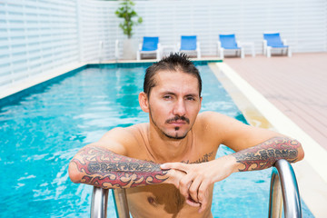 Portrait of man wirh tattoo in swimming pool.