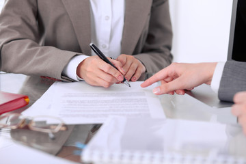 Group of business people and lawyers discussing contract sitting at the table. Woman chief is ...
