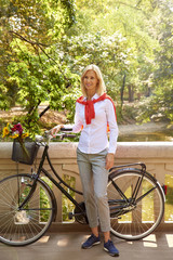 Obraz premium Woman with her bicycle. Full length portrait of middle aged businesswoman pushing her bike while commuting in the city.