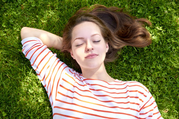Beautiful girl lying in the grass. Shot from above of a beautiful young woman relaxing while lying in the grass at summer.