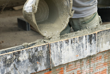 Worker pouring cement with lintel in construction site