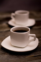 two small white cups of coffee on wooden background