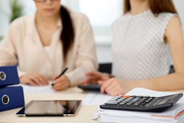 Two female accountants counting on calculator income for tax form completion hands closeup. Internal Revenue Service inspector checking financial document. Planning budget, audit  concept