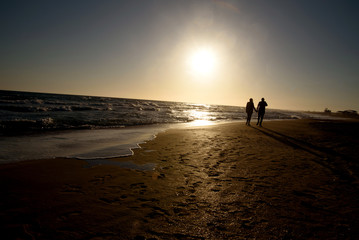 Naklejka premium Romantic couple on the beach at colorful sunset on background