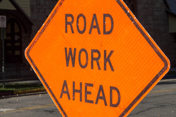 Road work ahead orange diamond sign in front of a building