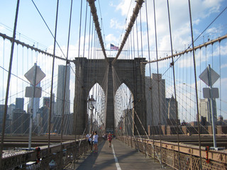 Brooklyn Bridge famous symbol of New York City with downtown Manhattan skyscrapers landscape, sky, clouds people during sunny day. Travel tourism popular destination background with empty copyspace