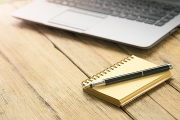 Business Creativity - Pen on the empty notebook and laptop on wooden table.