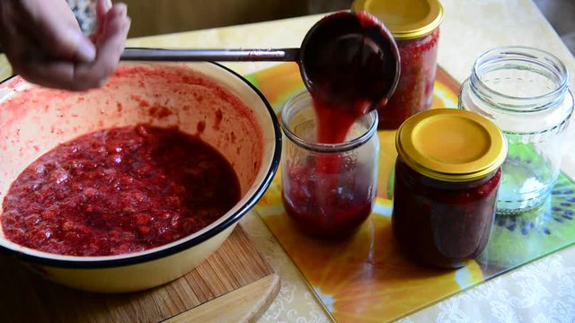 Woman puts handmade Strawberry jam in jar