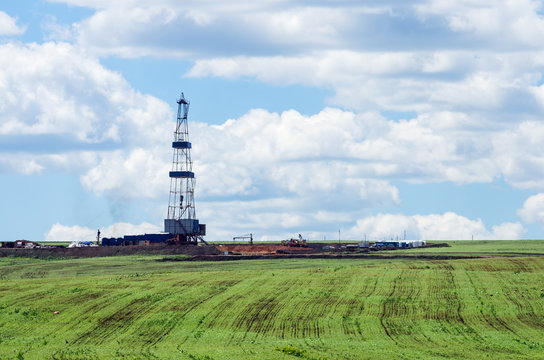 Oil rig among green fields. Spring