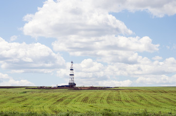 Fototapeta na wymiar Drilling rig among agricultural fields