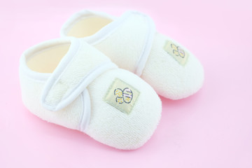 Baby shoes on light pink background