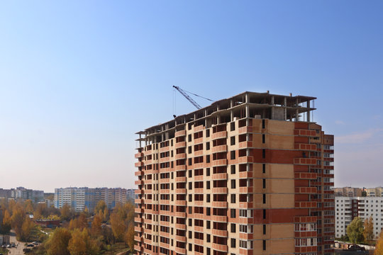 Tall brick building under construction at autumn sunny day, pure