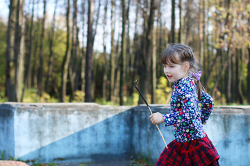 Naklejka premium Cute little girl in red skirt runs in sunny green park with old