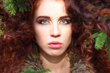 Young woman poses among fir branches in forest, shallow dof