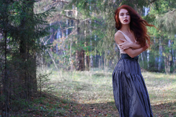 Sensual woman in skirt and belt poses on wind in sunny autumn fo