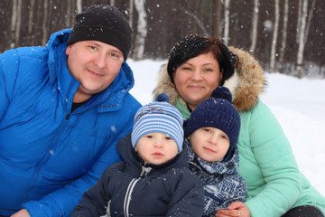 Happy family (father, mother, two sons) pose in winter day durin