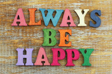 Always be happy written with colorful wooden letters on rustic surface
