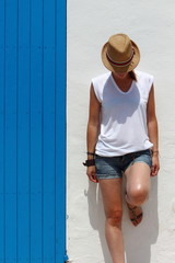 Young woman resting close to a blue wooden door in a typical village building, Formentera, Balearic...