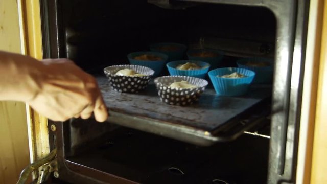 Woman puts dough in a cake pan in the oven in the kitchen