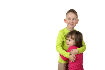 Boy stands and embraces little girl protecting her isolated on white background with free space for...