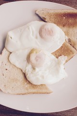 Obraz na płótnie Canvas Fried eggs on white toast - filter applied 