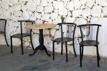 old chairs and white stone antique wall in greek village