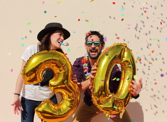 Cheerful couple celebrates a thirty years birthday with big golden balloons and colorful little...