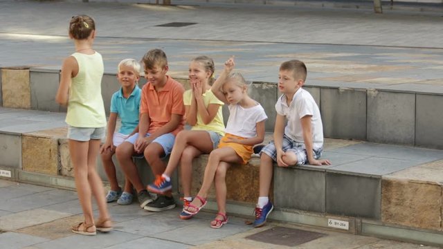 Smiling kids in school age playing charades outdoors


