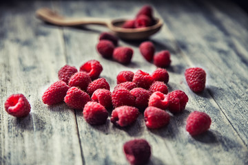 Ripe sweet raspberries in spoons on wooden table. Close up, top