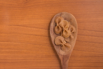 Wholegrain Farfalle into a spoon. wholemeal. Integral.