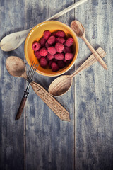 Ripe sweet raspberries in bowl on wooden table. Close up, top vi