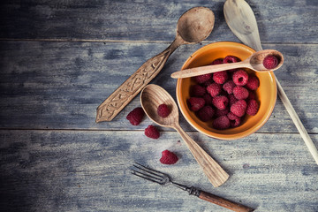 Ripe sweet raspberries in bowl on wooden table. Close up, top vi