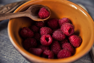 Ripe sweet raspberries in spoons on wooden table. Close up, top