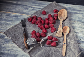 Ripe sweet raspberries in spoons on wooden table. Close up, top