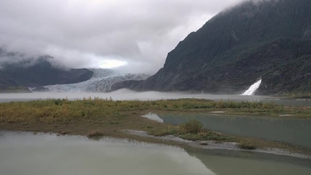 An establishing wide shot of Mendenhall Glacier near Juneau, Alaska on a foggy day.  	