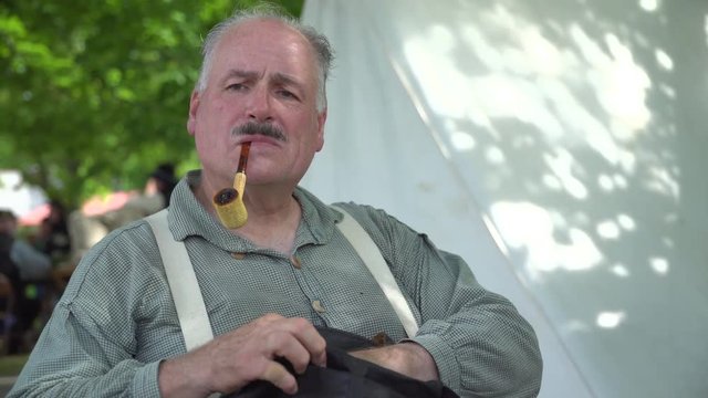 Civil War soldier smokes pipe in camp