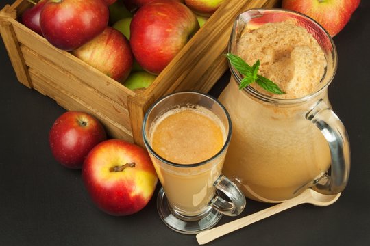 Fresh pressed apple juice unfiltered. Apple juice and apples on wooden table. A healthy juice for athletes. Autumn apple harvest.
