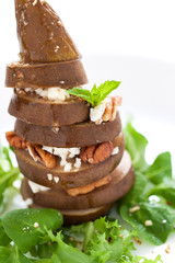 Baked pear with cheese, nuts and honey on a salad, closeup, selective focus