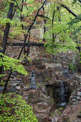 View of a rocky hill, small cascade and statue at the Gilsangsa Temple in Seoul, South Korea.