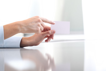 Hand showing blank business card, on desk