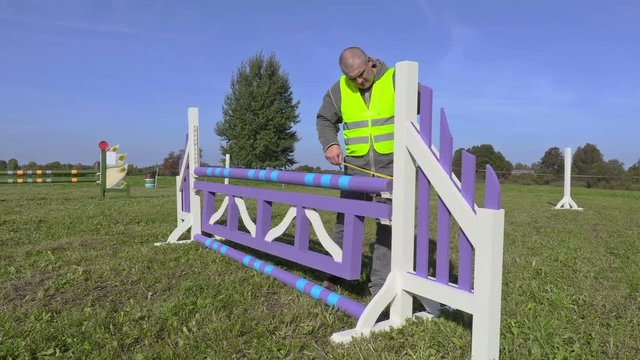 Horse handler with measure tape near hurdle