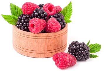 blackberries and raspberries spilled from wooden bowl isolated on white background