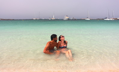 Young beautiful couple enjoys an early morning lonely bath in Espalmador beach, one of the most...