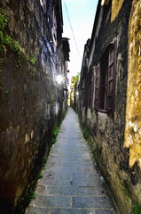 People passing between buildings in Hoi An, Vietnam (Movie color tone)