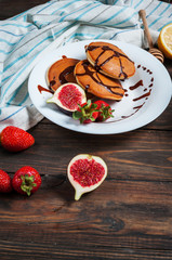pancakes with figs, strawberries on white plate closeup