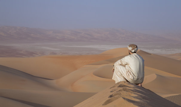 Man in kandura in a desert at sunrise