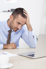Fototapeta premium Stressed businessman working at his desk in his office