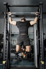 Fototapeta na wymiar Hombre con grandes músculos levantando peso mientras entrena en el gimnasio. Ponerse en forma.